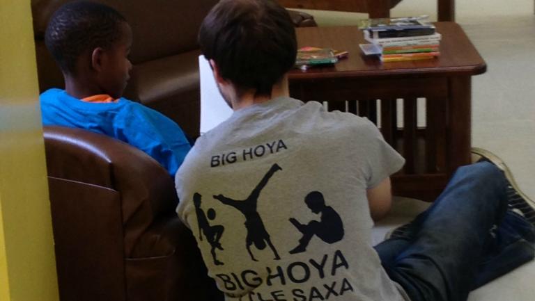 A male student displays the back of his Big Hoya Little Saxa t-shirt