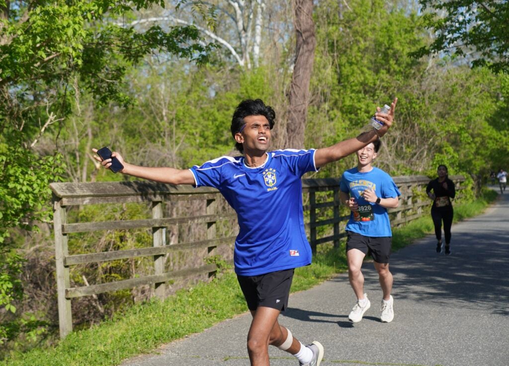 image of student running and celebrating after finishing ironmed 5k